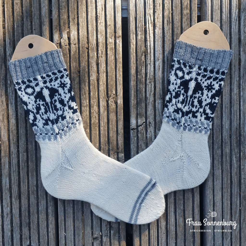 a pair of socks on a wooden surface - Auf den Nadeln im Juli