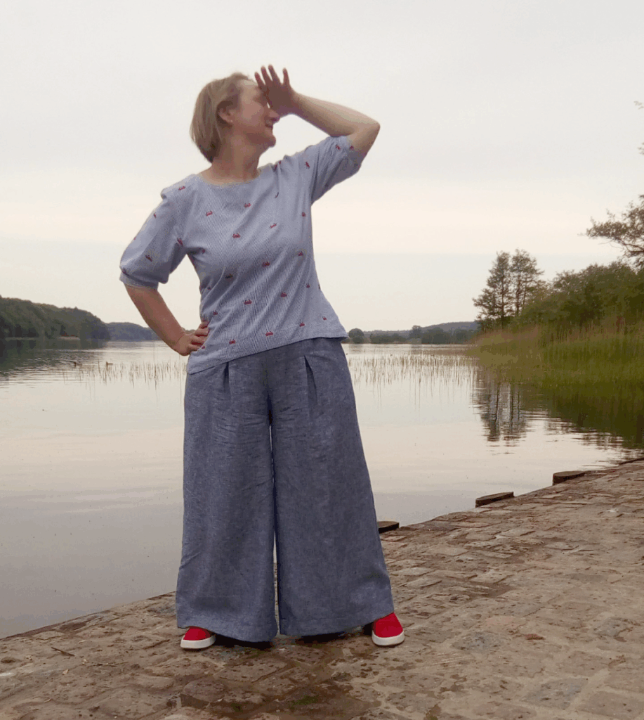 Frau am Wasser in modischer Kleidung. Pirkko Pants von Rosa P in blauem Leinen